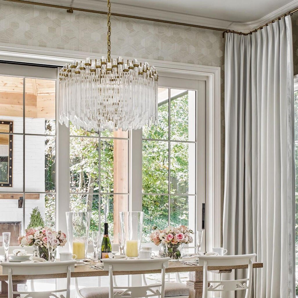 Interior view with Adele Chandelier – a statement of glamor above soft beige sofas and sunlit serenity