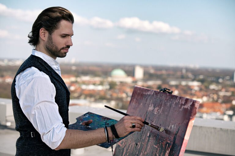Contemporary artist Martin Köster painting on a rooftop above the city, working on an original oil painting